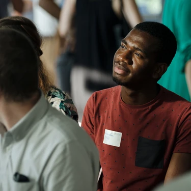 Student sits in the audience and looks towards a speaker on the stage.