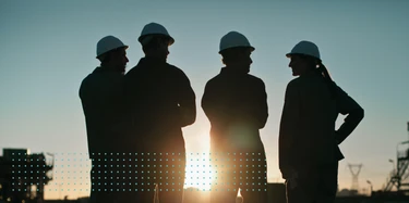 Personen mit Bauhelmen vor untergehender Sonne