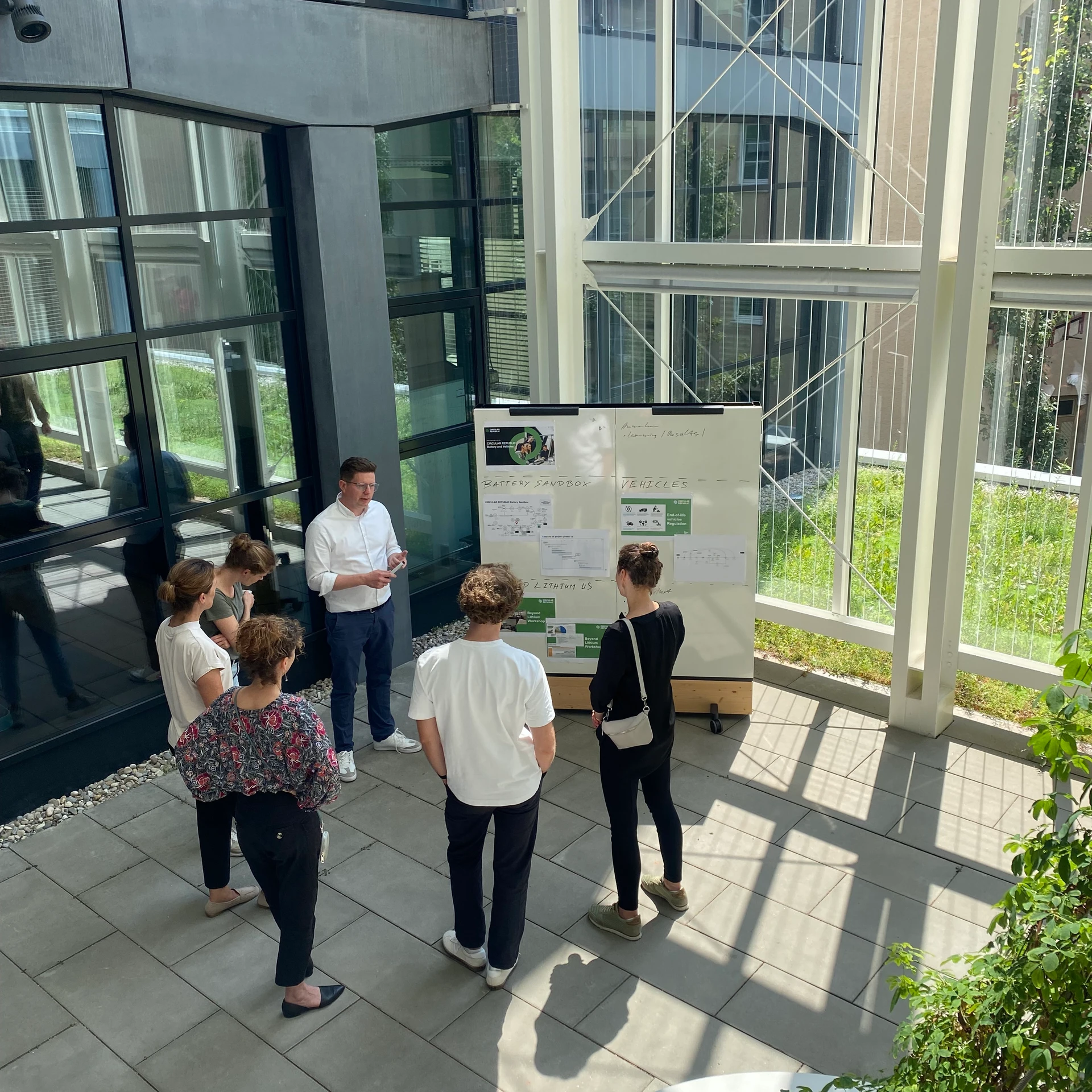 a group of people in the courtyard in front of a whiteboard