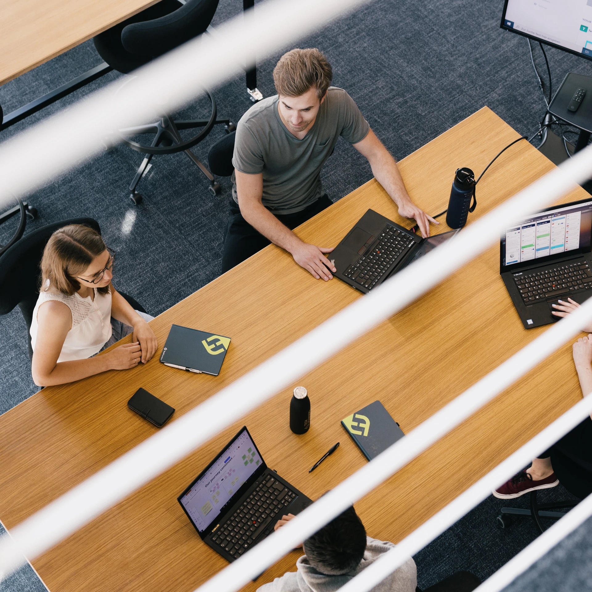 Blick von oben auf Personen mit Laptops am Tisch